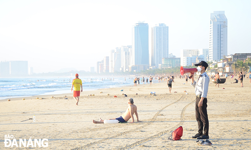   Beach staff are on duty to remind visitors to strictly abide by the regulations on COVID-19 prevention and control and handle incidents if any. Photo: THU HA.