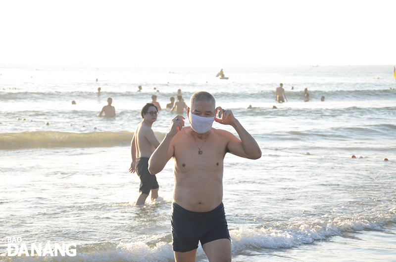  According to Deputy Head of the Management Board of Son Tra Peninsula and Da Nang tourist beaches, Tran Dai Nghia, thanks to the careful preparation, beach-goers’ awareness of pandemic prevention rules has improved significantly. In the photo: A resident wears a face mask right upon beach swimming. Photo: THU HA.