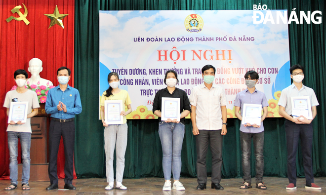 Municipal Labour Union Chairman Nguyen Duy Minh (2nd, left) and Vice Chairman Hoang Huu Nghi (3rd, right) presenting scholarships to outstanding pupils