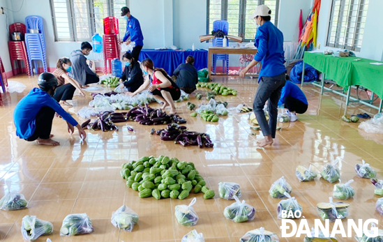 Các đoàn viên thanh niên và hội viên phụ nữ thôn Phú Sơn 1 (xã Hòa Khương) phân chia hàng cứu trợ để cấp phát cho người dân. 			     			            Ảnh: LÊ VĂN THƠM