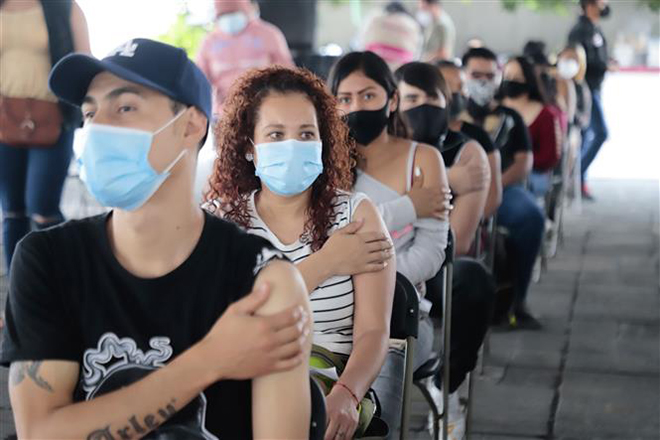  Người dân ngồi chờ theo dõi sau khi tiêm vaccine ngừa Covid-19 tại Nezahualcoyotl, Mexico ngày 19-8-2021. Ảnh: THX/TTXVN