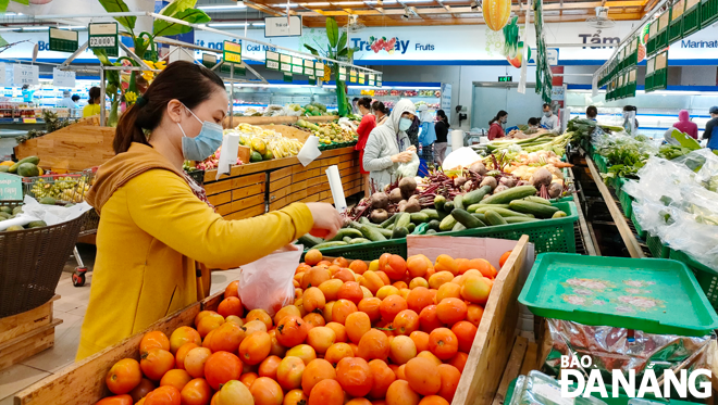 Vietnamese-produced goods have increasingly won the trust of customers. In photo: Shopper selecting domestically produced agricultural products at the Co.opmart supermarket in Thanh Khe District.