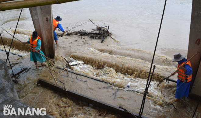 Công nhân Công ty TNHH MTV Khai thác Thủy lợi Đà Nẵng vớt rác, khơi thông tại đập dâng An Trạch để lũ thoát nhanh về hạ du. Ảnh: HOÀNG HIỆP