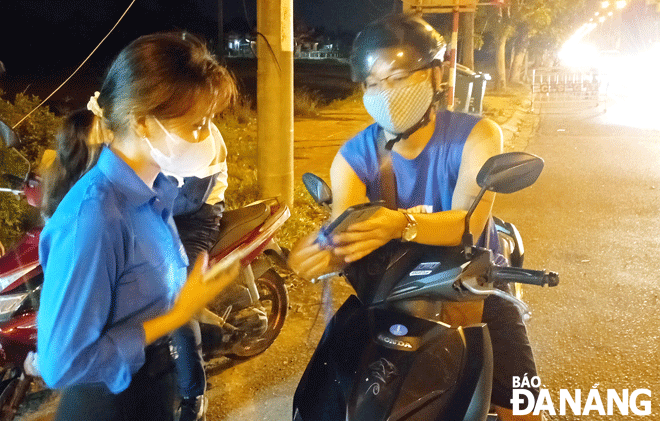 Anh Nguyễn Thanh Lên (phải) làm thủ tục về nhà tại chốt kiểm soát dịch trên quốc lộ 1A qua xã Hòa Phước, huyện Hòa Vang. 				            Ảnh: XUÂN SƠN