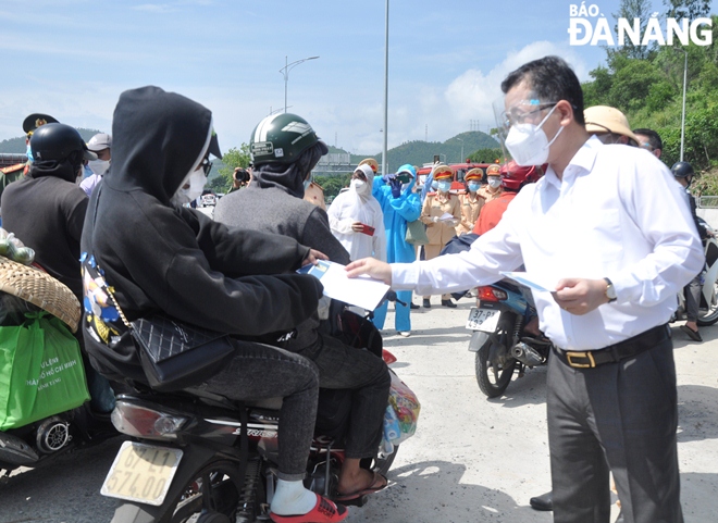 On behalf of the city's leaders and charity organisations, Secretary Quang (right) giving gifts of cash to people returning to their hometown from the South before they go through the Hai Van Tunnel. Photo: LE HUNG