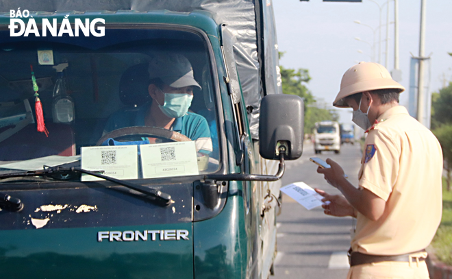 A traffic police officer pulling over a truck driver to check his COVID-19 certificate with QR Code. Photo: DAC MANH