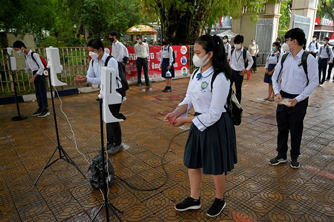  Học sinh khử khuẩn tay và đo thân nhiệt trước khi vào lớp học tại Phnom Penh, Campuchia ngày 15-9-2021. Ảnh: AFP/TTXVN