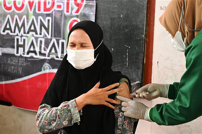  Nhân viên y tế tiêm vaccine ngừa Covid-19 cho người dân tại Banda Aceh, Indonesia. Ảnh: AFP/TTXVN