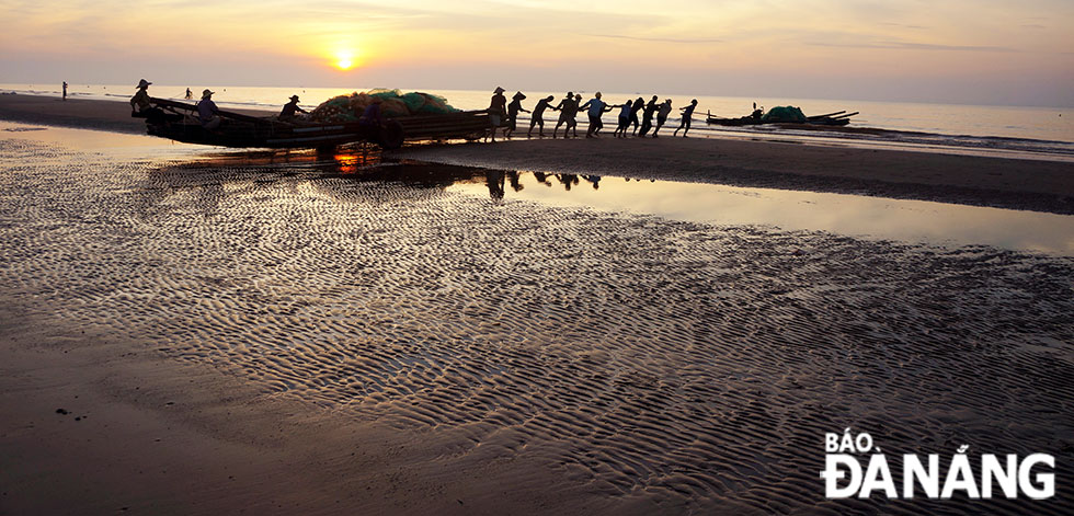 People are up early to push their fishing boat head to the ocean.