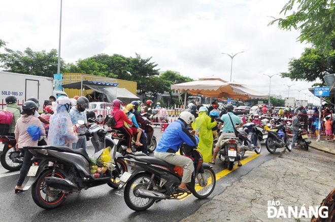 People are waiting for medical declarations to pass through a checkpoint set up at an entrance gate to Quang Nam Province on Tran Hung Dao Street in Dien Ngoc Ward, Dien Ban Town