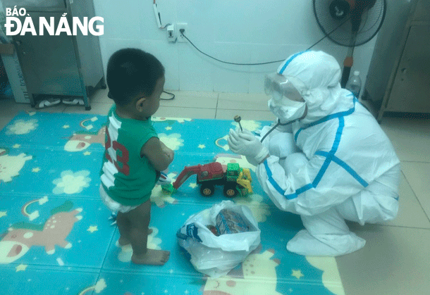 Doctor Tran Thi Thu from the Ward of Pediatrics at the Hoa Vang District Medical Centre is seen playing with a child patient infected with COVID-19.