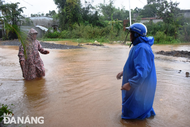People in Trung Son Village, Hoa Lien Commune, walk through flooded roadways to buy food for their families. Photo: HOANG HIEP