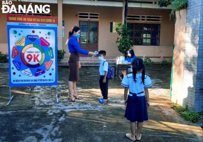  The first-graders of the Hoa Bac Primary School have their body temperature checked before entering the classroom.