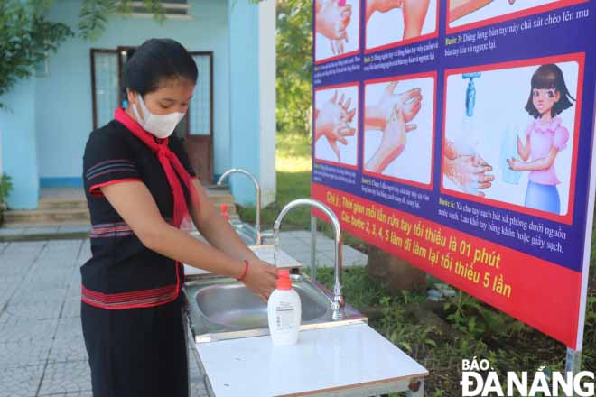 A ninth-grader washes her hand before entering the classroom.