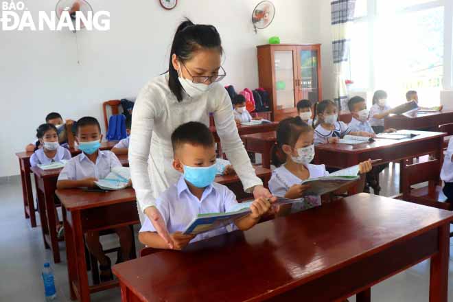 The first-graders are instructed how to properly hold books.