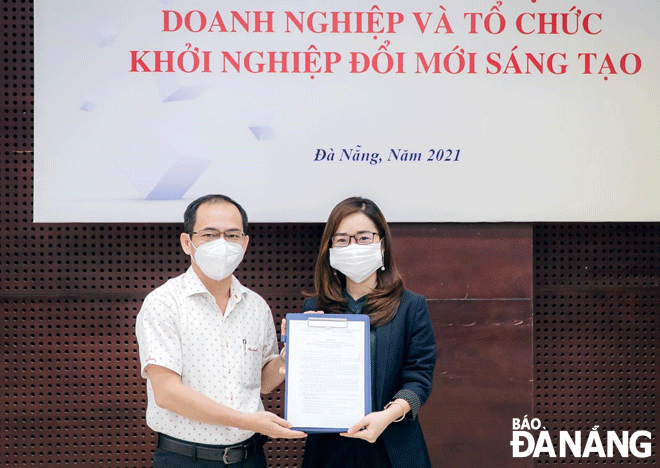Giám đốc Sở Khoa học và Công nghệ thành phố Lê Đức Viên (bên trái) ký kết hỗ trợ khởi nghiệp đổi mới sáng tạo với Vườn ươm doanh nghiệp Đà Nẵng DNES. (Ảnh chụp tháng 6-2021) Ảnh: MAI QUẾ