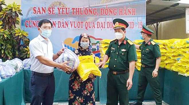 Đại diện Ủy ban MTTQ Việt Nam quận Hải Châu (trái) trao quà hỗ trợ cho hộ gia đình khó khăn trong đợt dịch thứ 4. (Ảnh do đơn vị cung cấp)	