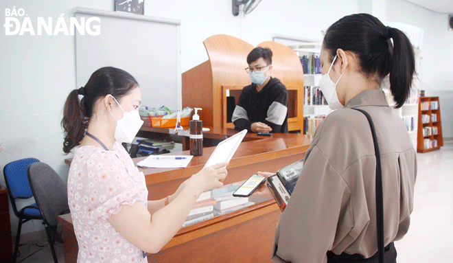 An officer of the Da Nang General Science Library (on the left) scans the medical declaration QR code for readers. Photo: Xuan Dung 