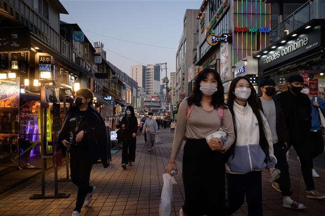 Người dân di chuyển trên phố ở Seoul, Hàn Quốc ngày 16-11-2020. Ảnh: AFP/TTXVN