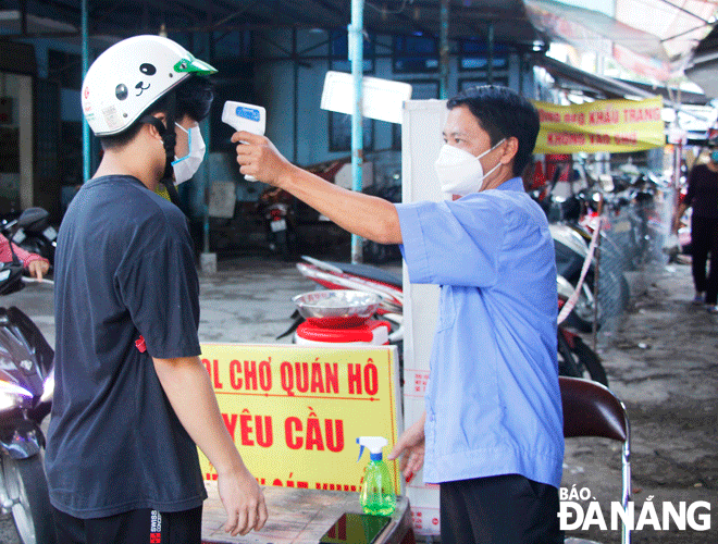 Công tác phòng, chống dịch tại các chợ trên địa bàn quận Thanh Khê được thực hiện chặt chẽ. TRONG ẢNH: Ban quản lý chợ Quán Hộ, phường Thanh Khê Đông đo thân nhiệt cho người dân vào chợ.  Ảnh: XUÂN DŨNG	