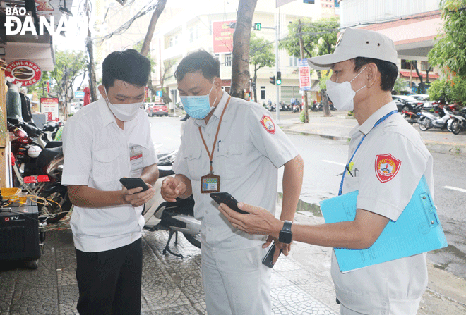 Lực lượng quy tắc đô thị phường Phước Ninh kiểm tra việc quét mã QR tại các cửa hàng, cơ sở kinh doanh trên địa bàn trong sáng 28-10.  Ảnh: VĂN HOÀNG	
