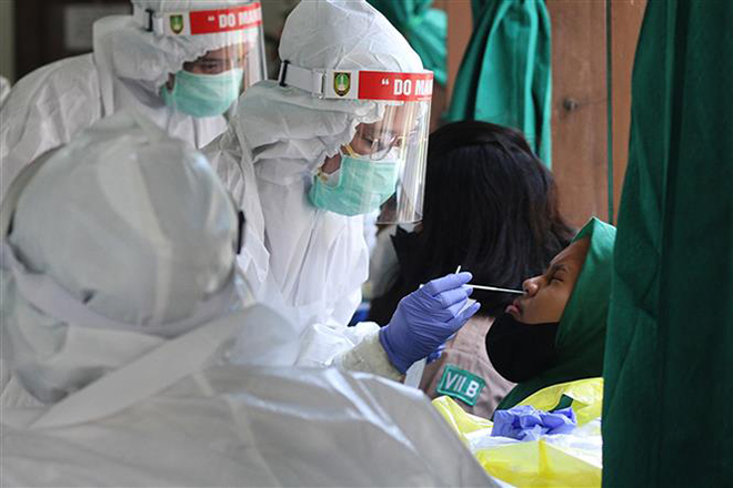  Nhân viên y tế lấy mẫu xét nghiệm Covid-19 cho người dân tại Surakarta, Indonesia, ngày 22-10-2021. Ảnh: THX/ TTXVN