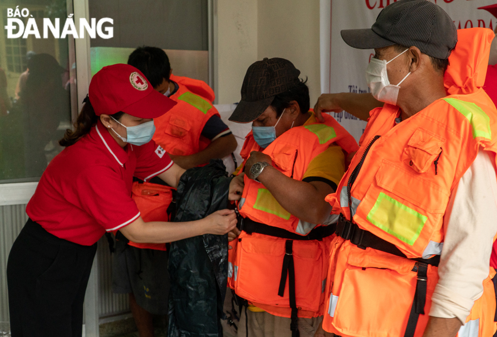 A staff of the Da Nang Red Cross Society guiding fishermen to put on multifunctional life jackets