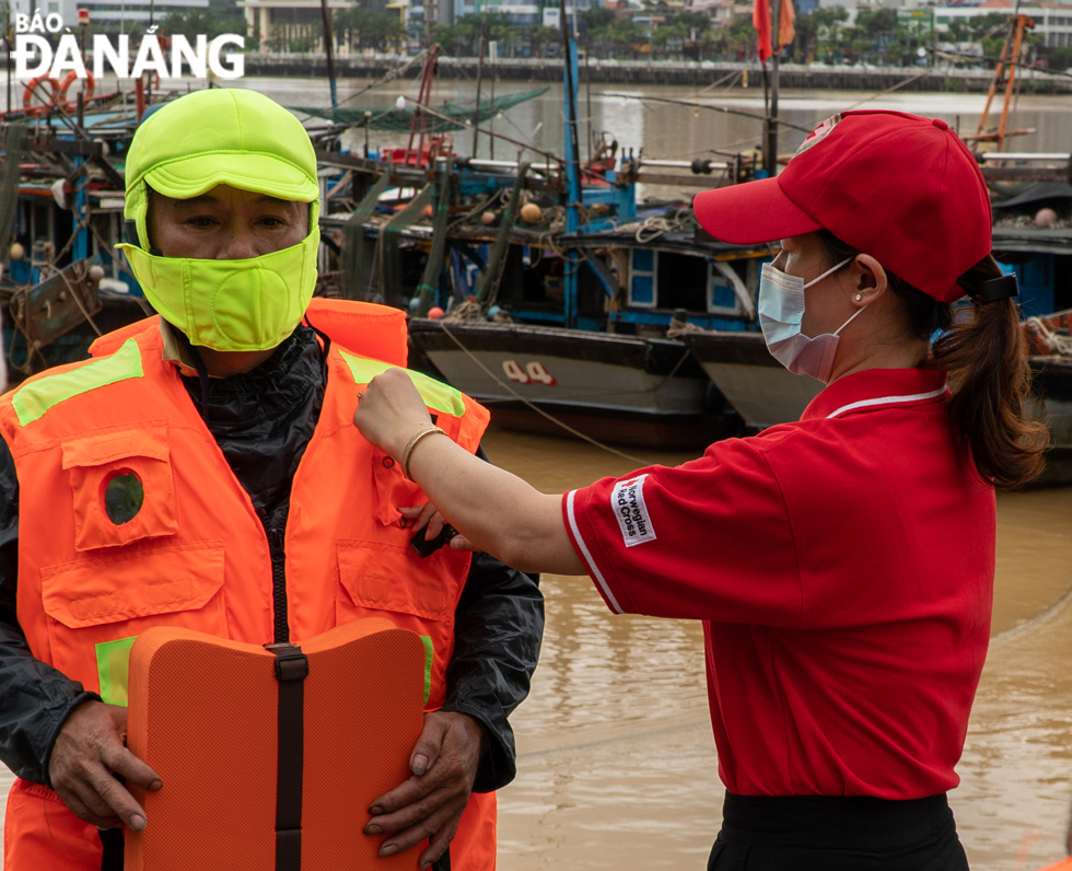 A fisherman is guided to wear a life jacket properly