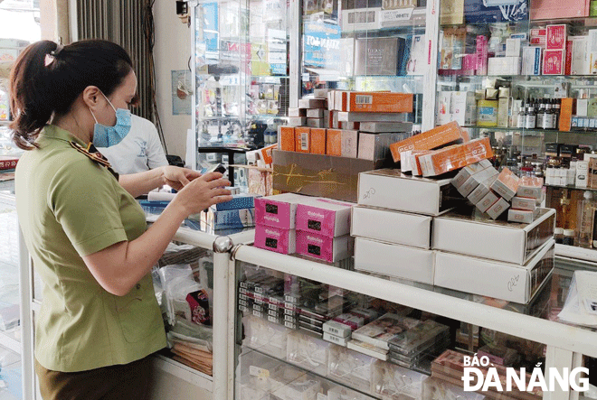 A staff member from the Da Nang Market Management Bureau checking the origins of products on sale a store in Lien Chieu District