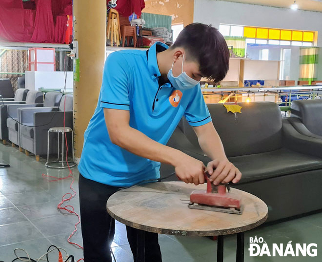 A secondhand store employee is handling old tables before selling. Photo: Mai Hien