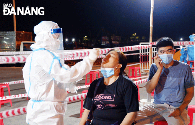 Health workers in Son Tra district taking nasal swab samples of fishermen and traders at the Tho Quang Fishing Wharf for COVID-19 testing after some active cases were detected here. Photo: PHAN CHUNG