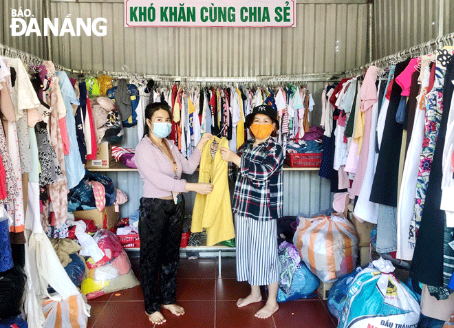 Chị Lê Thị Hoàng Ngân (bên trái) ở phường Hòa Minh, quận Liên Chiểu  giúp bà Nguyễn Thị Kiếm chọn lựa áo ấm từ “Gian hàng 0 đồng” của mình.  Ảnh: N.QUANG	