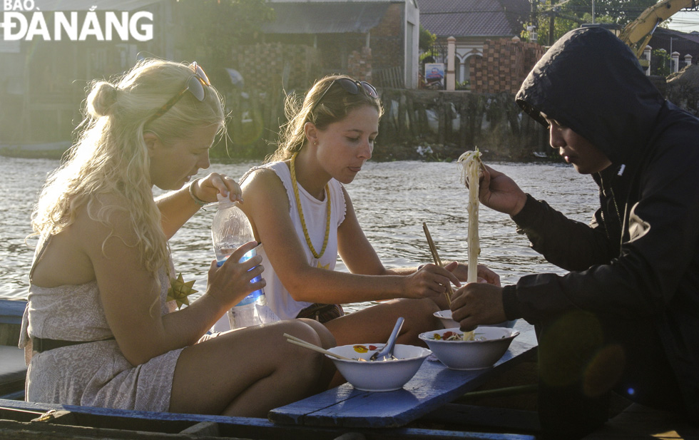 Foreign tourists enjoying culinary dishes right on a tourist boat at the Cai Rang Floating Market