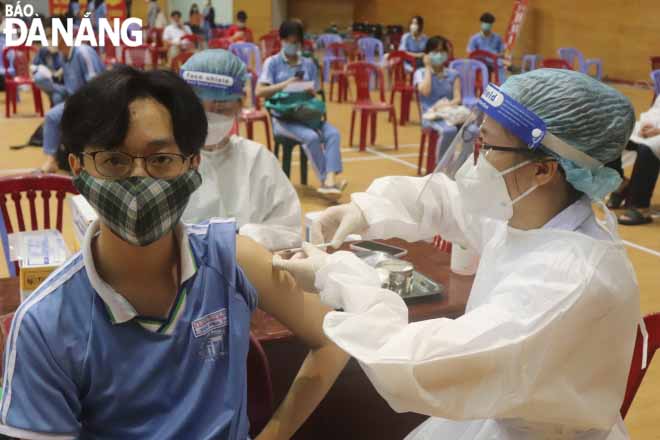 A healthcare professional giving a first dose of the Pfizer BioNTech COVID-19 vaccine to a senior high school student. Photo: NGOC HA