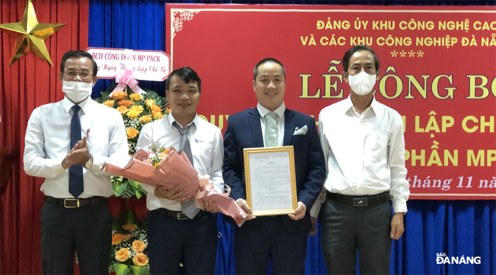 Phó Bí thư Thường trực Đảng ủy KCNC và CKCN Đà Nẵng Đàm Quang Hưng (ngoài cùng bên trái) trao quyết định thành lập và tặng hoa chúc mừng Bí thư và Phó bí thư chi bộ cơ sở công ty CP MP Pack. Ảnh H.N