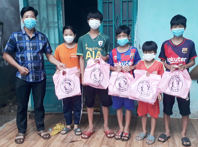 Mr. Kinh (left) gives Mid-Autumn Festival gifts to the children of laborers working in his acacia forest. Photo: N.H