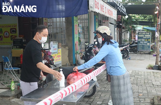 Một quán ăn trên đường Khúc Hạo (phường Nại Hiên Đông) thực hiện giăng dây, trang bị nước rửa tay sát khuẩn cho khách đến mua hàng trong sáng 14-11.
