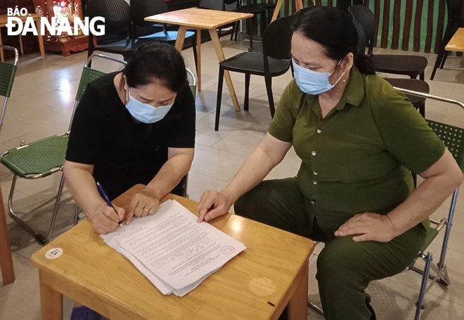 The owner of a coffee shop in Nai Hien Dong Ward signing a commitment not to providing  table service.