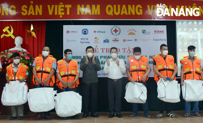 Former President Truong Tan Sang (4th left) and Da Nang Party Committee Secretary Nguyen Van Quang (4th right) presenting sets of multifunctional life jackets to poor fishermen in Son Tra District’s Nai Hien Dong Ward. Photo: LE VAN THOM