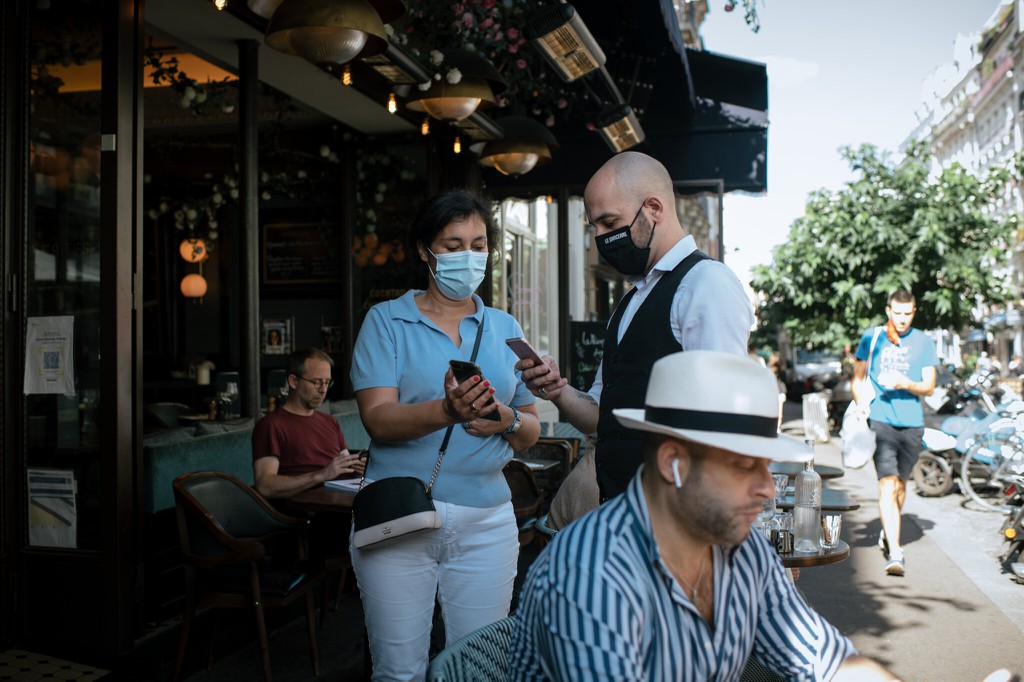 Nhân viên kiểm tra thẻ xanh y tế của khách tại một quán cà phê ở Paris (Pháp). Ảnh: New York Times