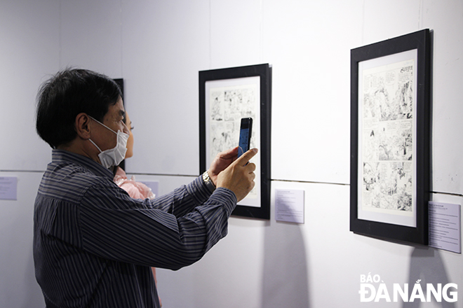 Khách tham quan triển lãm chụp ảnh lưu lại những tác phẩm của họa sĩ Vĩnh Khoa - Vink đang được Bảo tàng Mỹ thuật Đà Nẵng trưng bày. Ảnh: XUÂN DŨNG