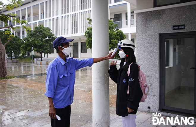 Học sinh Trường THPT Sơn Trà được bảo vệ đo thân nhiệt, sát khuẩn tay trước khi vào cổng. Ảnh: XUÂN DŨNG