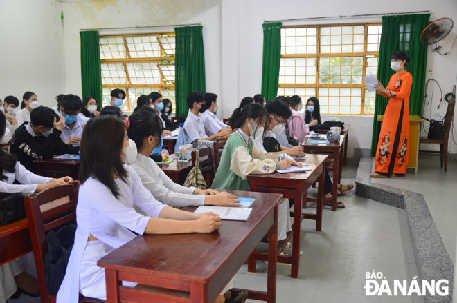 A homeroom teacher recommends her students to regularly wear a face covering and disinfect their hands, do not share food or drink as well as avoid gathering/socializing when coming to/leaving school and during class breaks in order to keep themselves and others safe and healthy during the school year. Photo: XUAN SON