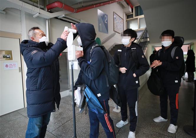 Kiểm tra thân nhiệt nhằm ngăn chặn sự lây lan của dịch COVID-19 tại một trường học ở Seoul, Hàn Quốc, ngày 22/11/2021. Ảnh: YONHAP/TTXVN