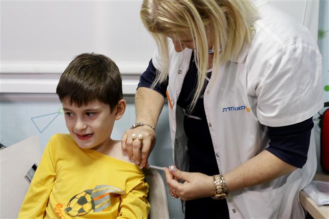 Nhân viên y tế tiêm vaccine phòng COVID-19 của hãng dược Pfizer/BioNTech cho trẻ em tại Tel Aviv, Israel, ngày 22/11/2021. Ảnh: AFP/ TTXVN