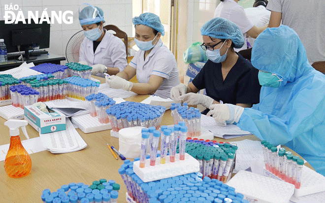 Staff members of the Da Nang Center for Disease Control and Prevention (CDC) handle swab samples collected from local residents for COVID-19 testing. Photo: LE HUNG