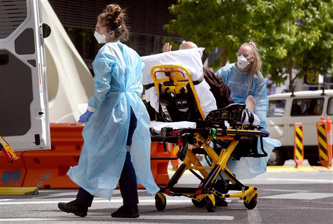 Nhân viên y tế chuyển bệnh nhân Covid-19 tại bệnh viện ở Melbourne, Australia. Ảnh: AFP/ TTXVN