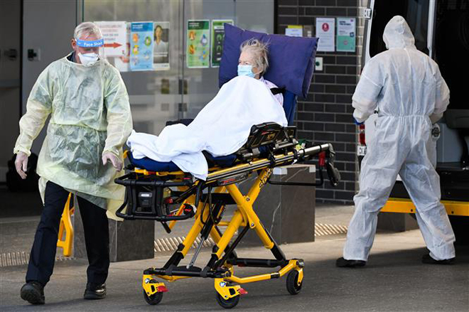  Nhân viên y tế chuyển bệnh nhân Covid-19 tại Melbourne, Australia. Ảnh: AFP/ TTXVN