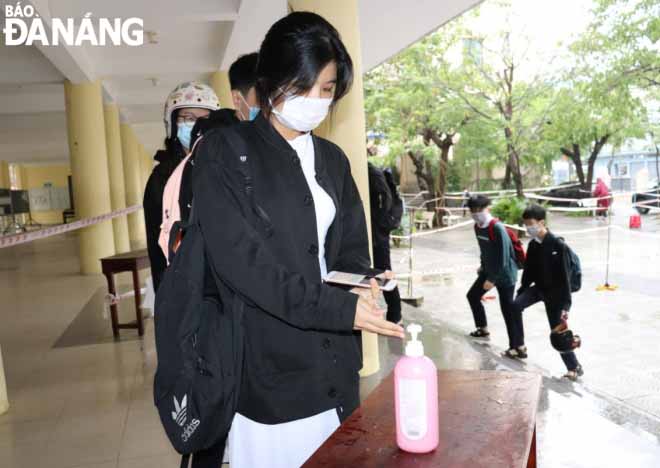 Students from Hoang Hoa Tham Senior High School disinfect their hands before entering their classes