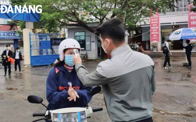 Students of Hoang Hoa Tham Senior High School have their body temperatures measured before entering the classes